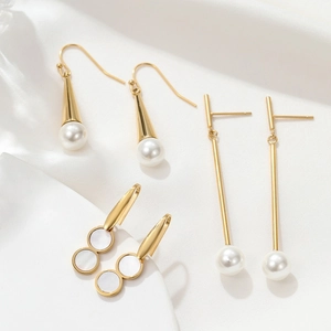 Close-up of elegant gold earrings with white pearls on a soft white silk background