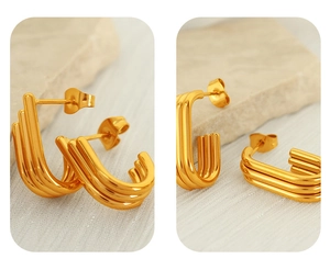 Macro detail of gold U-shaped ribbed stud earrings with triple-layered geometric design