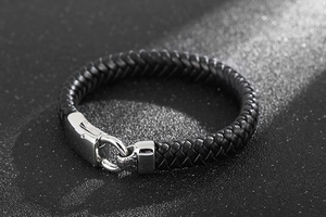 Gros plan sur la texture du cuir tressé noir et le fermoir en acier argenté du bracelet