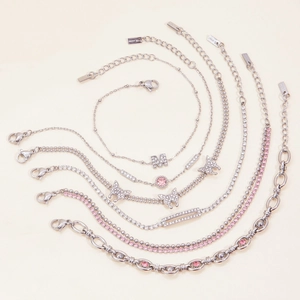 Detailed close-up of stacked stainless steel bracelets with pink zircon charms and heart shapes