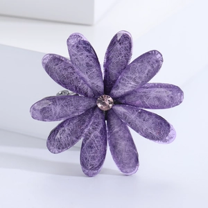 Detail of purple acrylic flower brooch with pink rhinestone center on white platform