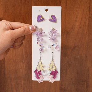 Detailed view of 3-pair earring set with purple hearts, flowers and butterfly charms