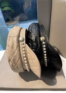 Detail of quilted leather baker boy hats with decorative pearl chains and metal buttons