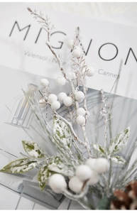 Detailed view of snowy white berries, frosted green leaves, and pine cones for decor