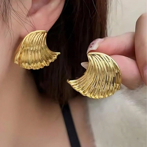 Gold ocean wave textured fan-shaped earrings worn by a model for a vintage look