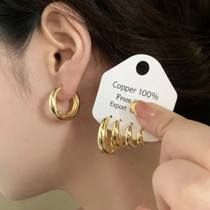 Close-up of minimalist gold hoop earring set in copper with multiple sizes on display
