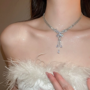 Close-up of a silver butterfly tassel necklace with zircons on a model in white feathers