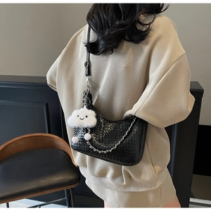 Detailed shot of black woven bag with metal chain strap and a white cloud charm pendant
