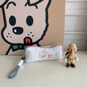Detail of embroidered rabbit and strawberry on white quilted pouch with zipper closure