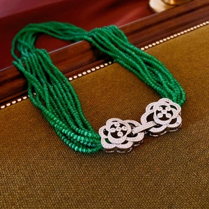 Detailed macro shot of vintage multi-strand green beaded necklace with silver floral charms