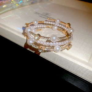 Macro shot of multi-layered gold bracelet with pearls and sparkling rhinestones