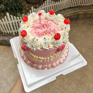 Gâteau d'anniversaire rose de style coréen avec volants de crème blanche et cerises.