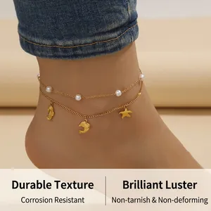 Double-layer gold anklet with pearls and sea animal charms on a sandy beach
