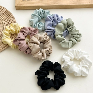 Detailed close-up of 8 assorted satin scrunchies in pastel colors on a soft background