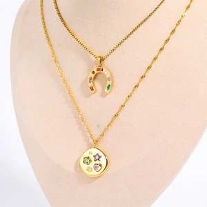 Detail of layered gold horseshoe and star pendants with vibrant colorful gemstones