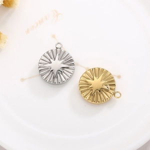 Golden and silver circular stainless steel starburst pendants on a Cancer zodiac plate