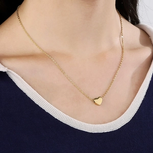 Elegante goldene Halskette mit Herzanhänger präsentiert am Schlüsselbein der Frau