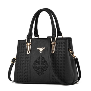 Detail of woven PU leather texture and embroidered pattern on a black handbag