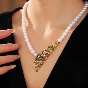 Détail d'un collier de perles vintage avec pendentif fleur en or et pierres précieuses