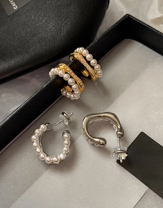Macro shot of gold and silver C-shaped hoop earrings with pearls and crystals