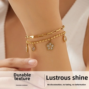Close-up of double-layer gold plated bracelet with diamond-set flower pendants