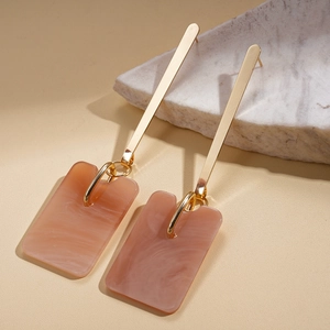 Macro view of long rectangular marble resin earrings with elegant golden metal studs