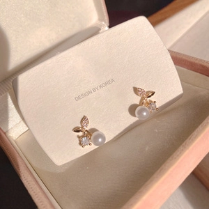 Macro detail of cherry shaped gold earrings with white pearl and sparkling zircon accents