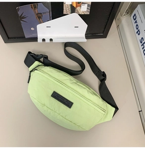 Detail of light green waterproof nylon cross-body bag with adjustable black strap and buckle