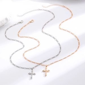 Close-up of gold and silver Figaro chain necklaces with micro-paved zircon cross pendants