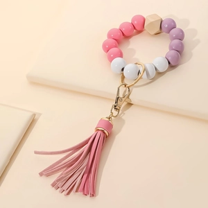 Detail of pink and purple wood bead keychain bracelet with a pink leather tassel charm