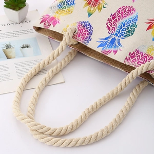 Detail of cotton rope handles and colorful pineapple print on a canvas tote bag