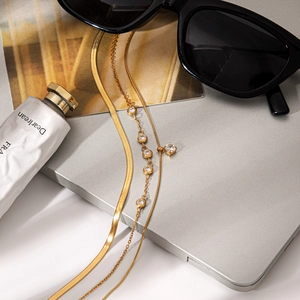 Detailed view of triple-layered gold titanium steel necklaces with cubic zirconia on a desk