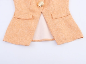 Détail de la texture tweed et bouton coquillage doré sur une veste sans manches orange