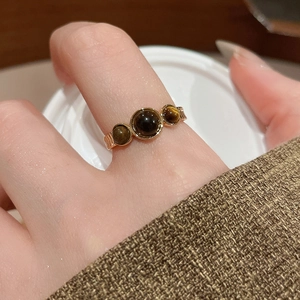 Detail shot of vintage 18k gold-plated ring with three polished tiger eye stones on finger
