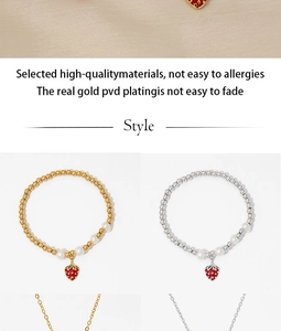 Detail von PVD-vergoldeten Erdbeeranhängern und Perlen auf allergiefreiem Schmuckset