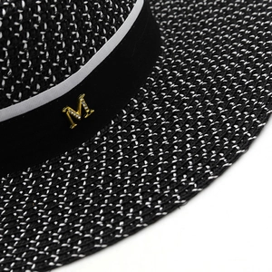 Flat top straw boater hat with black and white texture and rhinestone M metal logo
