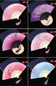 Close-up of assorted folding fans with floral patterns, tassels and bamboo ribs