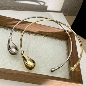 Detail of minimalist gold and silver open chokers with oversized water drop pendants