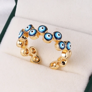 Detailed close-up of gold-plated evil eye ring with blue enamel in a white velvet box