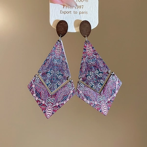 Detail of bohemian geometric wood earrings with ethnic rhombus patterns and stud design