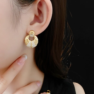 Gros plan de boucles d'oreilles rondes en plaqué or avec zircons et textures en éventail