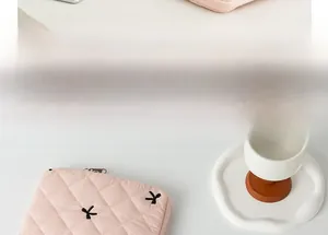Pink quilted tablet sleeve with black bow embroidery and zipper detail in a clean setting