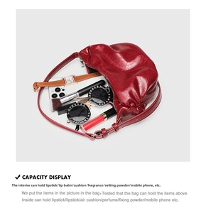 Spacious interior of red pleated leather bag showing phone, sunglasses and cosmetics
