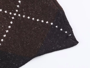Macro shot of dark brown and black knit fabric with white geometric jacquard pattern