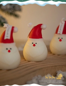 Detail of a Santa Claus shaped candle with red hat and card tag for holiday decor
