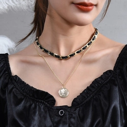Detail of layered gold coin pendant and black woven leather chain necklace on model