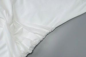 Close-up of white ribbed knit fabric featuring a twist knot detail and soft pleats