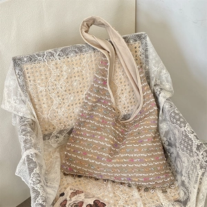 Close-up of bohemian woven tote bag with colorful sequins and seashell pendant detail