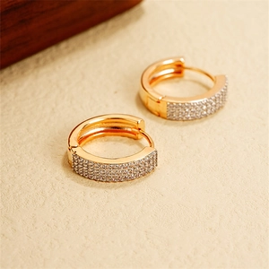 Macro shot of gold U-shaped hoop earrings with sparkling multi-row pavé crystals
