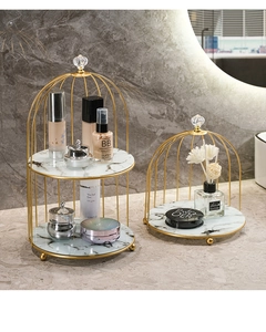 Detail of gold birdcage makeup organizer with white marble shelves on a luxury vanity